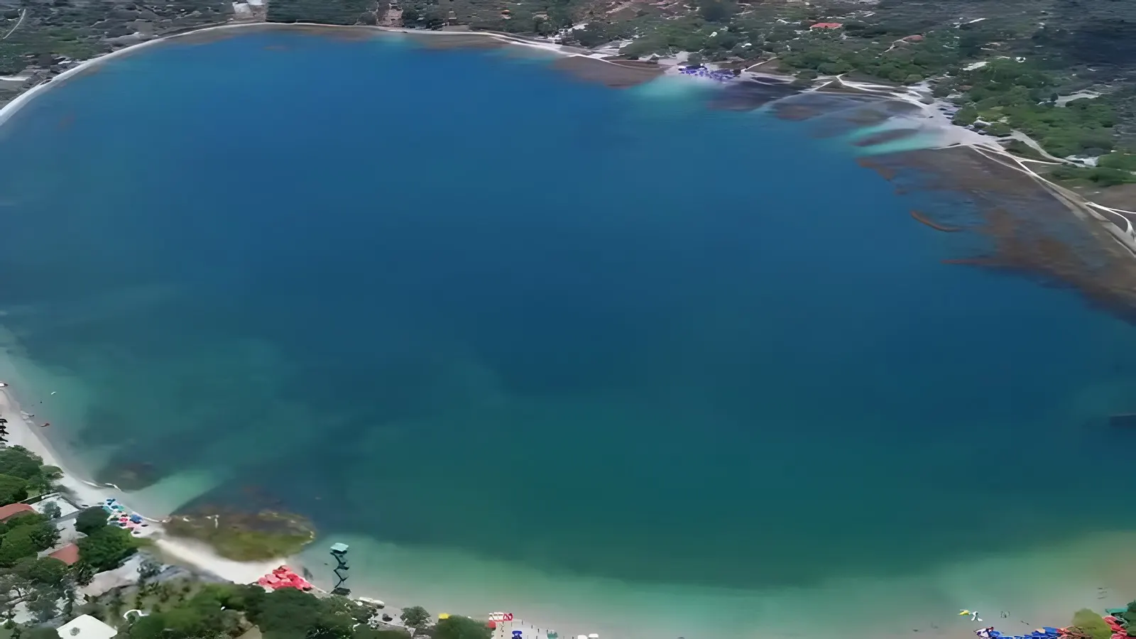Vista aérea da Lagoa do Carcará, em Nísia Floresta (RN), com a faixa de areia branca e as barracas na margem